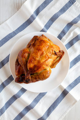 Homemade traditional rotisserie chicken on white plate, top view. Flat lay, overhead, from above.