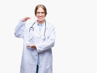 Fototapeta premium Beautiful young blonde doctor woman wearing medical uniform over isolated background gesturing with hands showing big and large size sign, measure symbol. Smiling looking at the camera