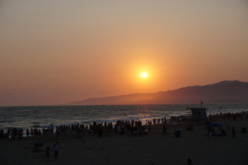 Atardecer de verano ocaso en playa con gente 