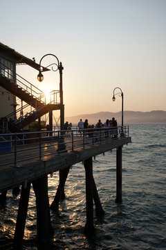 Muelle y playa en atardecer con colores c&aacute;lidos y gente