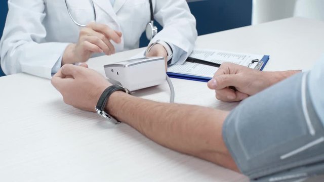 cropped view of female doctor measuring blood pressure of man with tonometer in clinic