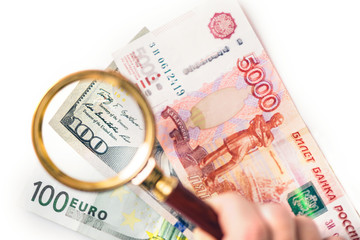Hundred dollar under a magnifying glass on the bacdrop euro and ruble banknotes. Сoncept of the main international currency