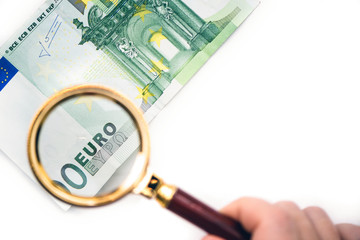 Hundred euro bill under a magnifying glass in the human hand. Concept