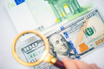 Hundred dollar under a magnifying glass on the bacdrop euro and ruble banknotes. Сoncept of the main international currency