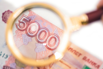 Banknote of five thousand russian rubles under a magnifying glass in the human hand. Concept