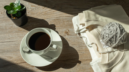 coffee cup and coat on wooden table in the light morning