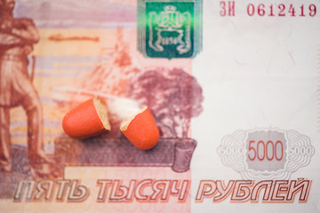 The two halves of the red pill lie on the banknote of five thousand russian rubles.  The concept.