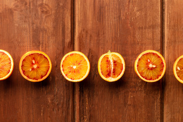 A closeup photo of organic blood oranges, shot from above on a dark rustic wooden background with...