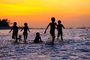 children playing in water at sunset