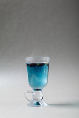Blue tea Anchan in an Irish glass on a gray background. Cup of Butterfly pea tea, pea flowers, blue pea. Healthy, detox