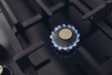 Cost of gas, concept crisis. Gas stove with coins in flame. The cost of methane. Gas coins more...