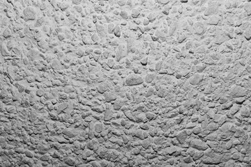 Black and white whitewashed concrete wall interspersed with stones