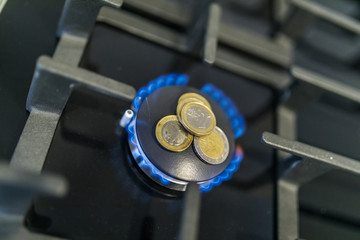 Cost of gas, concept crisis. Gas stove with coins in flame. The cost of methane. Gas coins more expensive. Gas Payment.