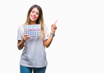 Young beautiful woman holding menstruation calendar over isolated background very happy pointing with hand and finger to the side