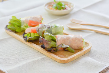 Salad roll with Green and red oaks, slice carrot, sausage, tuna on wooden tray with spicy dipping (Chili, Garlic and fish sauce). Healthy food.