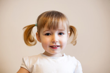 cute smiling child girl with two pigtails and quiff closeup portrait