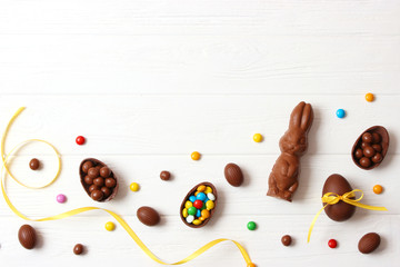  Easter composition with chocolate eggs and chocolate rabbit on wooden background, place for text 