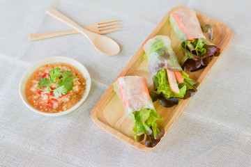Salad roll with Green and red oaks, slice carrot, sausage, tuna on wooden tray with spicy dipping (Chili, Garlic and fish sauce). Healthy food.