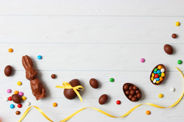 Naklejka na ściany i meble Easter composition with chocolate eggs and chocolate rabbit on wooden background, place for text 