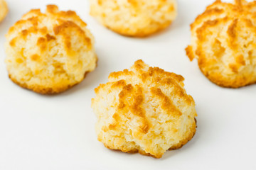 Homemade fresh delicious coconut macaroons cookies with golden crust on white kitchen table. Holiday pastry baking. Minimalist clean image. Poster banner recipe template with copy space