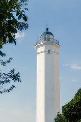 White lighthouse against the blue sky on a sunny day