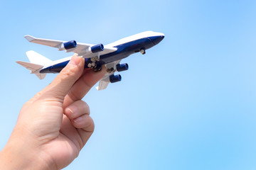 Airplane model in hand on sunny sky. Concepts of travel, transportation