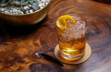 Alcoholic old fashioned cocktail with orange slice and lemon peel garnish