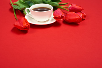 Fototapeta na wymiar red flowers bunch is on red background with cup of coffee - love and holiday concept