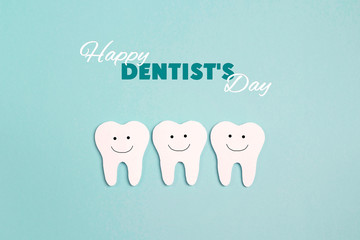Dentist day concept with white paper teeth on blue background.