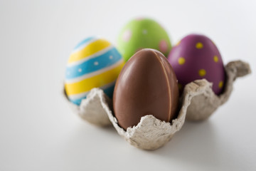 easter, holidays, tradition and object concept - close up of chocolate and colored eggs