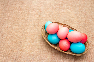 Easter eggs concept, table arrangement decoration. Pink (rosy) and blue eggs in wicker basket on...