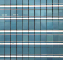 The glass facade of skyscraper with many identical windows. Same blue glasses structure of house...