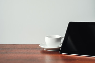 Desk at home office. Black tablet, white mug on a wooden table. Concept - work at home, freelancer. Copy space, minimal style