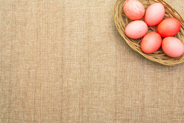 Easter eggs concept, table arrangement decoration. Pink (rosy) eggs in wicker basket on cloth...