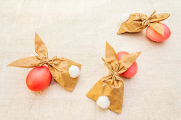 Easter bunny (rabbit) paper gift egg wrapping idea. Handicraft (homemade) concept for children (kids). On vintage cloth (linen) background