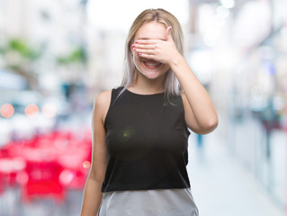 Fototapeta premium Young blonde woman over isolated background smiling and laughing with hand on face covering eyes for surprise. Blind concept.