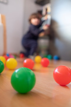 vertical colour balls on floor with blurred child on the back