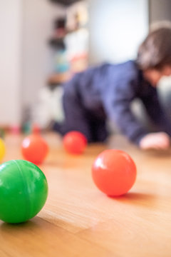 vertical colour balls on floor with blurred child on the back