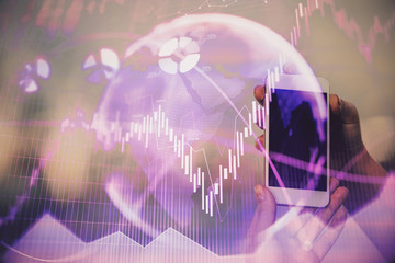Double exposure of businessman using cell phone and stock market charts. Financial concept.