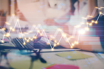 Hands typing on laptop. Business and Financial concept. Double exposure of stock market charts.
