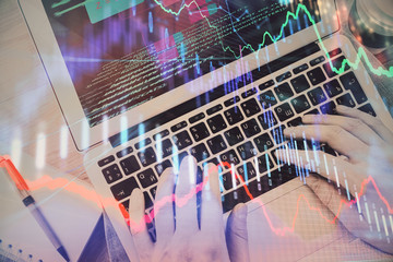 Hands typing on laptop. Business and Financial concept. Double exposure of stock market charts.
