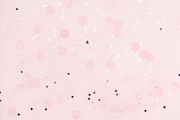 Pink confetti and stars and sparkles on pink background. Top view, flat lay. Copyspace for text. Bright and festive holiday background. For Christmas, New year, Mother's day.
