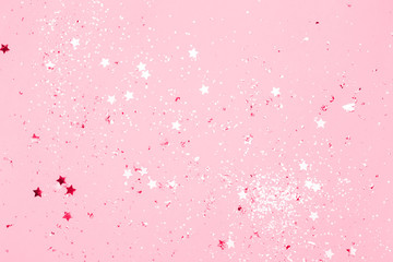 Pink confetti and stars and sparkles on pink background. Top view, flat lay. Copyspace for text. Bright and festive holiday background. For Christmas, New year, Mother's day.