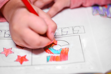 A girl learns to count, a girl colors a number five with a pencil.