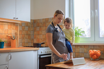 Mother with her baby girl looking for recipe on digital tablet