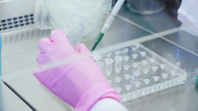 Close up footage of female hand fills test tube with the green sample. UHD footage of scientific experiment.