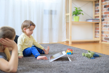 Mother and baby are looking to play and read tablet computer