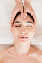 attractive woman getting face massage with closed eyes at spa