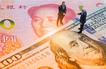 Miniature business men with US dollar and China Yuan banknote on cooperate meeting for trade war.Copy space and business concept. -Image.