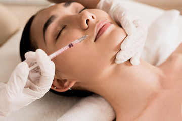 close up of attractive asian woman getting beauty injection at clinic